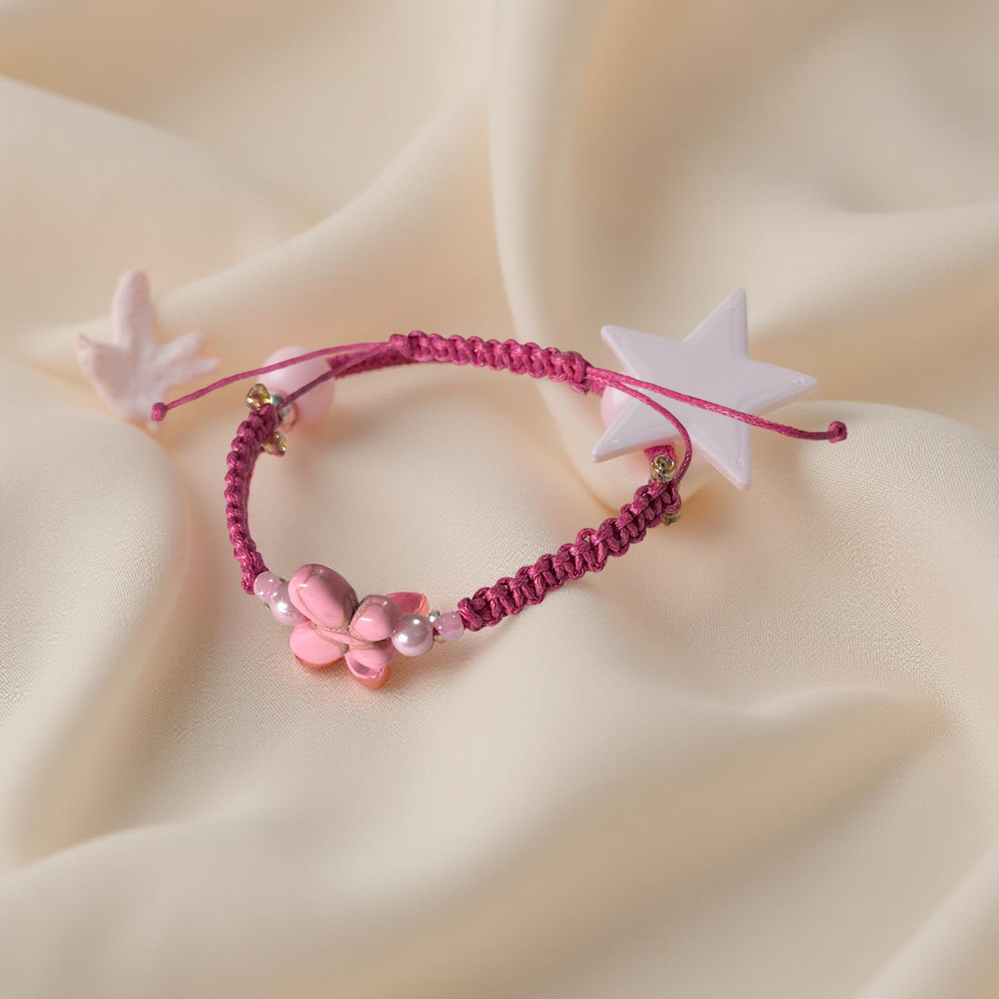 Pink bracelet with star and flower charms on a beige fabric background