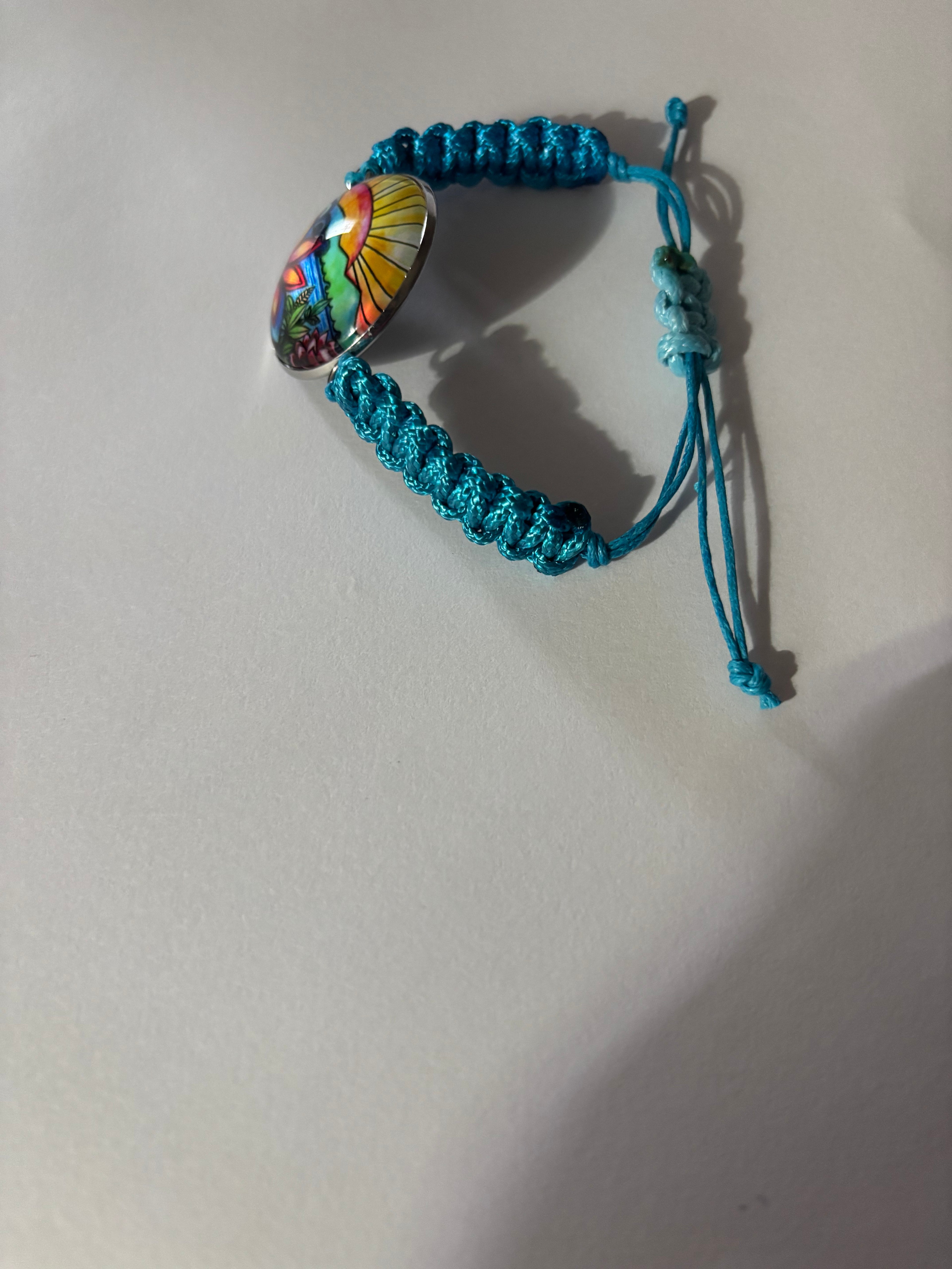 Blue braided bracelet with a colorful bead on a light gray background