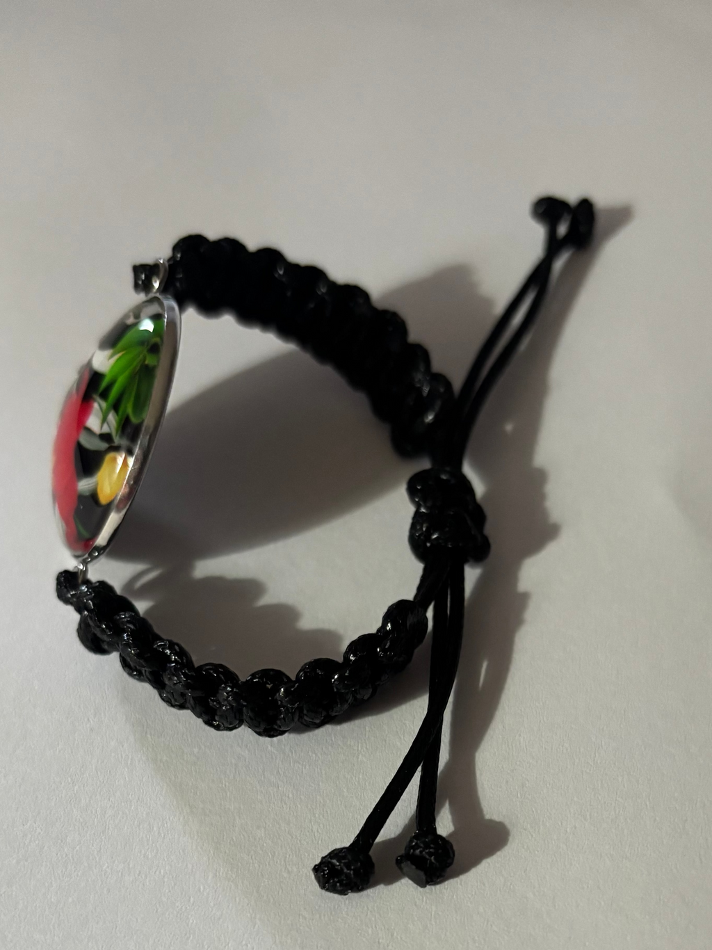 Black beaded bracelet with a colorful pendant on a white background