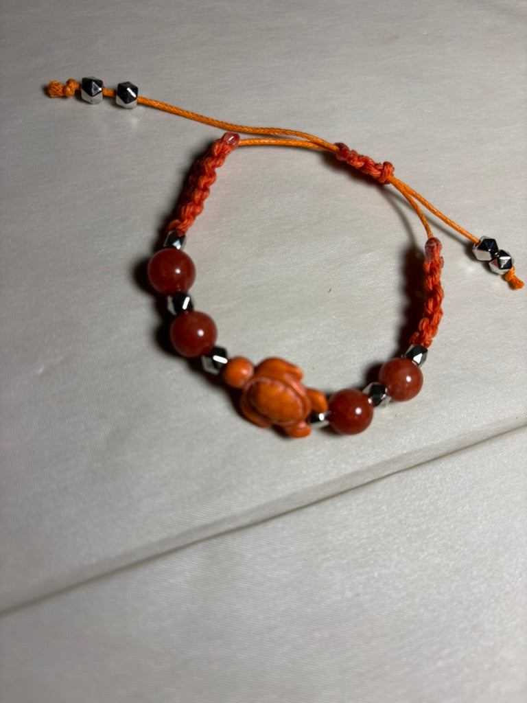 Bracelet with orange beads and a small figurine