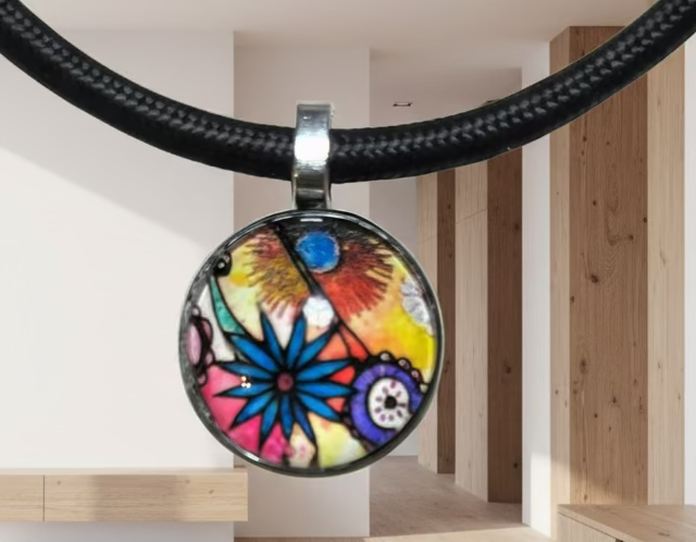 Colorful floral pendant on a black cord against a neutral background