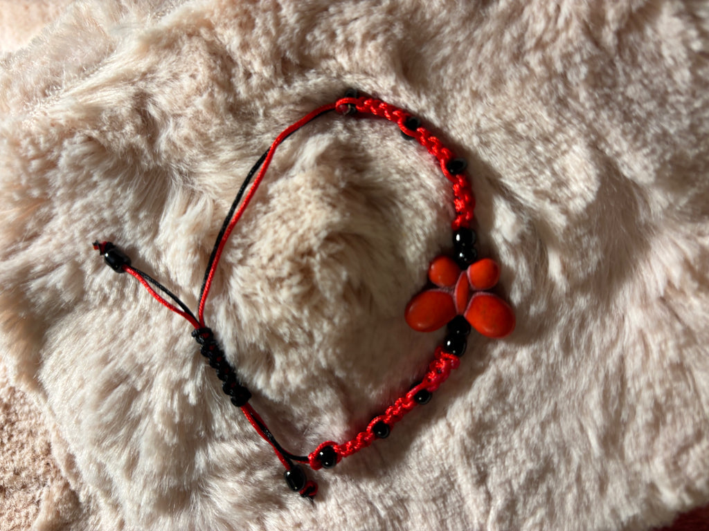 Red and black beaded bracelet on a fluffy white surface
