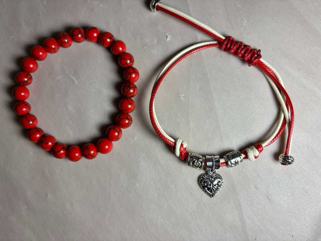 Two bracelets: one with red beads and the other with a heart charm 