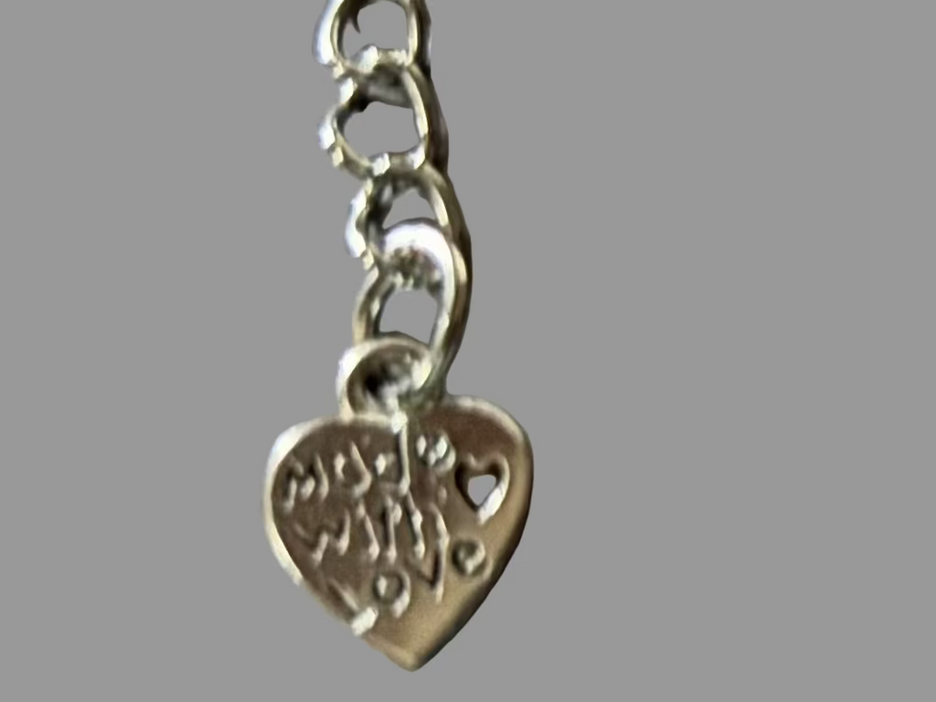Silver heart-shaped charm with engraved text on a gray background