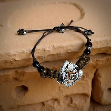 Bracelet with rose charm and beads on a stone surface