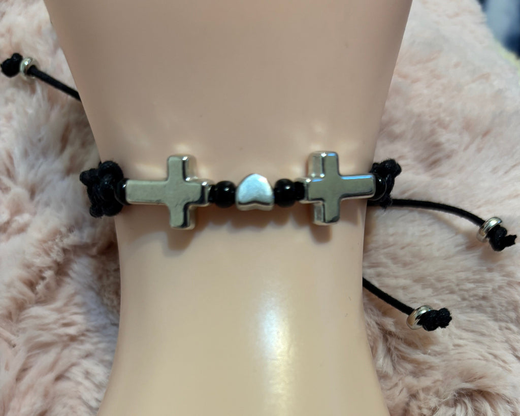 Bracelet with cross designs on a mannequin wrist against a soft background