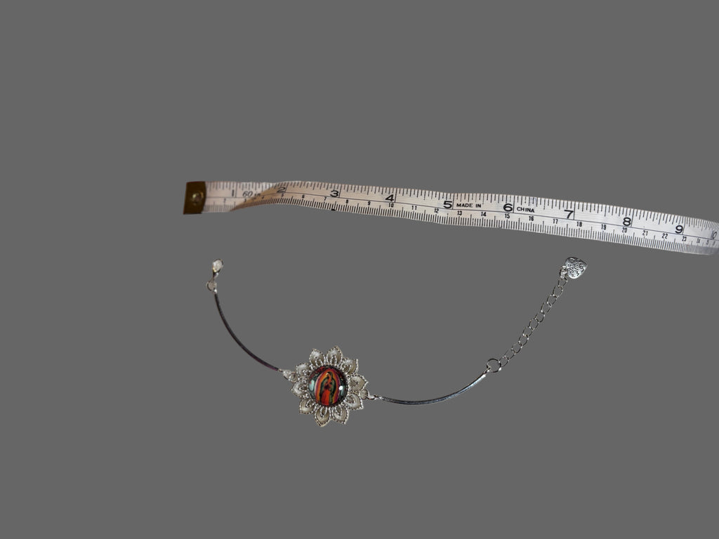 Necklace with a red stone and silver chain on a gray background, accompanied by a measuring tape.