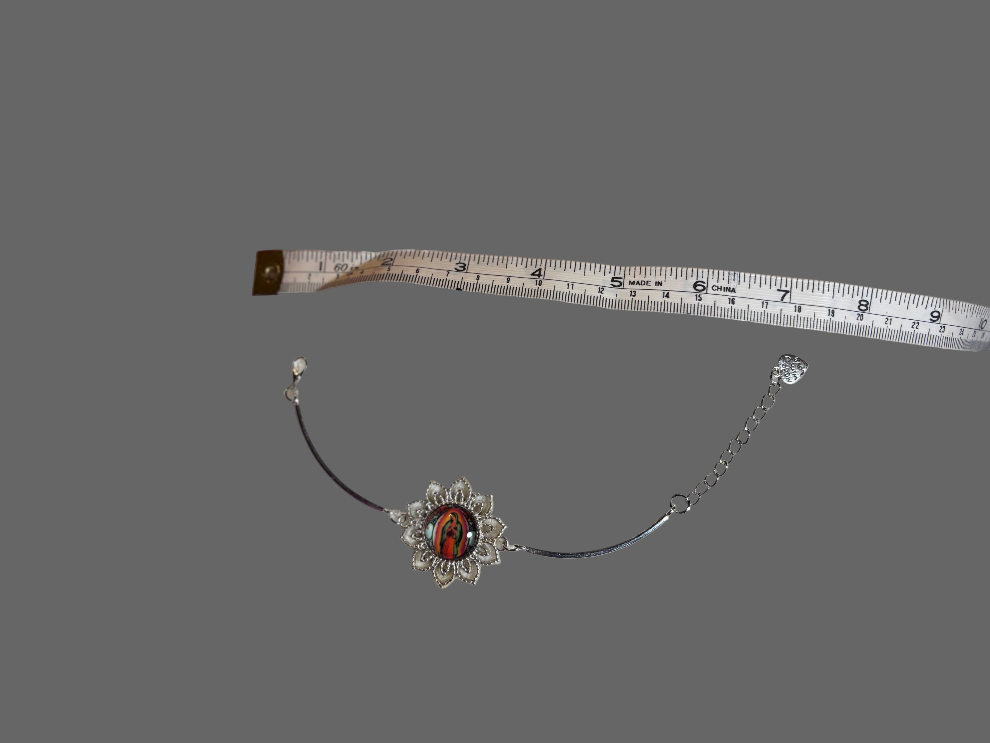 Necklace with a red stone and silver chain on a gray background, accompanied by a measuring tape.