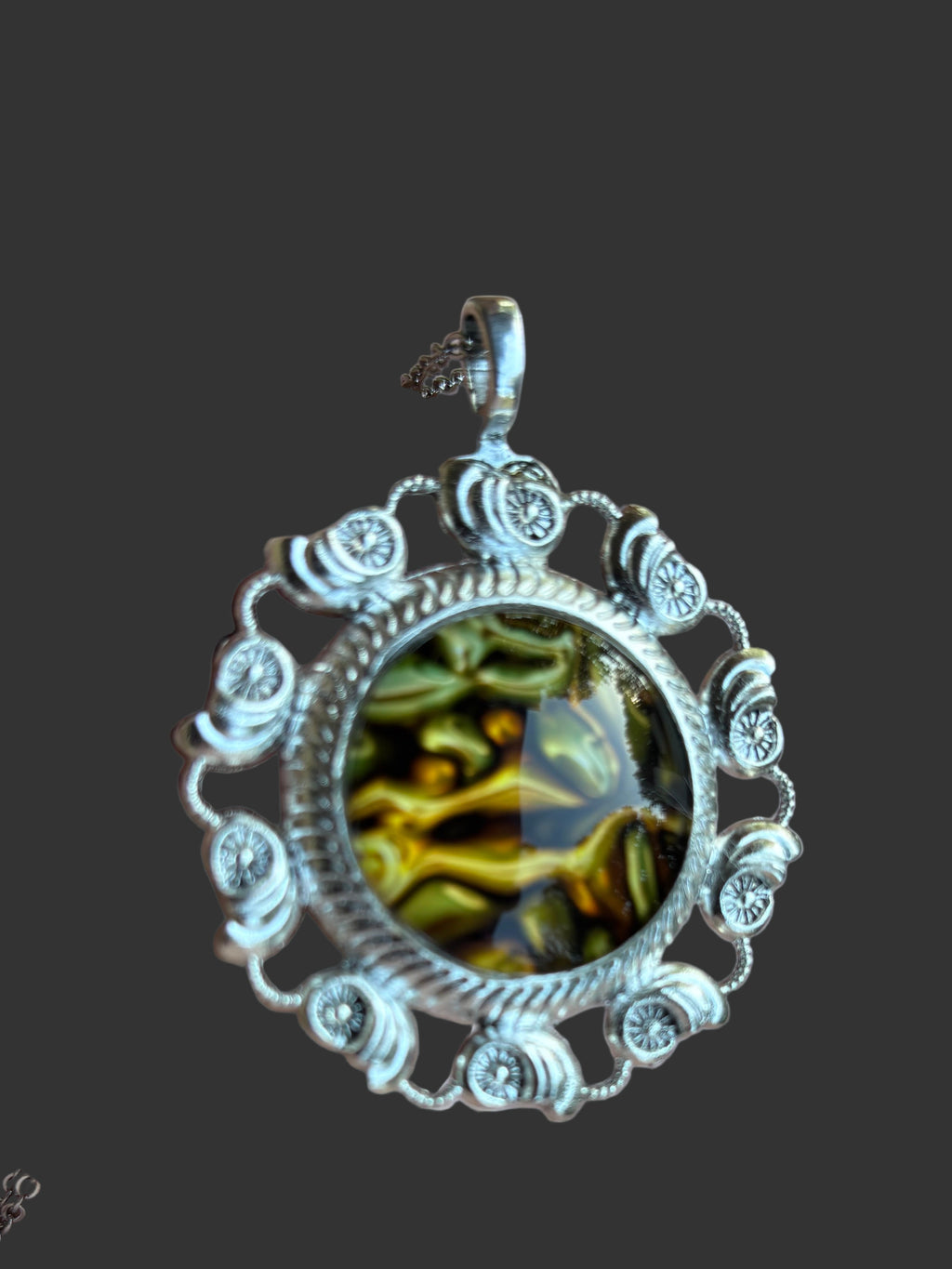 Silver pendant with a green gemstone on a dark background