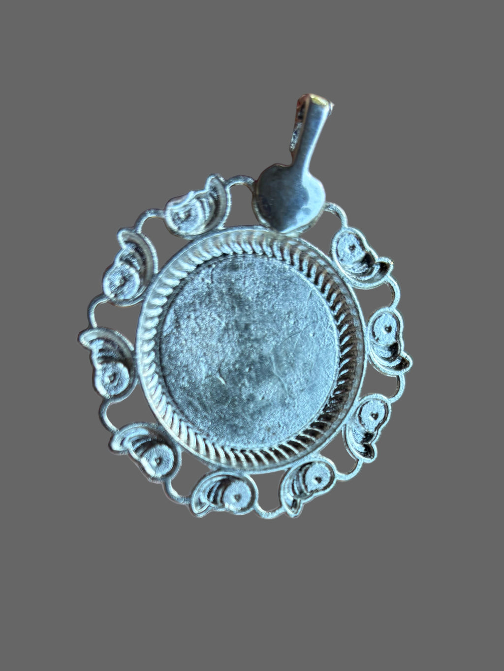 Decorative silver pendant on a plain background