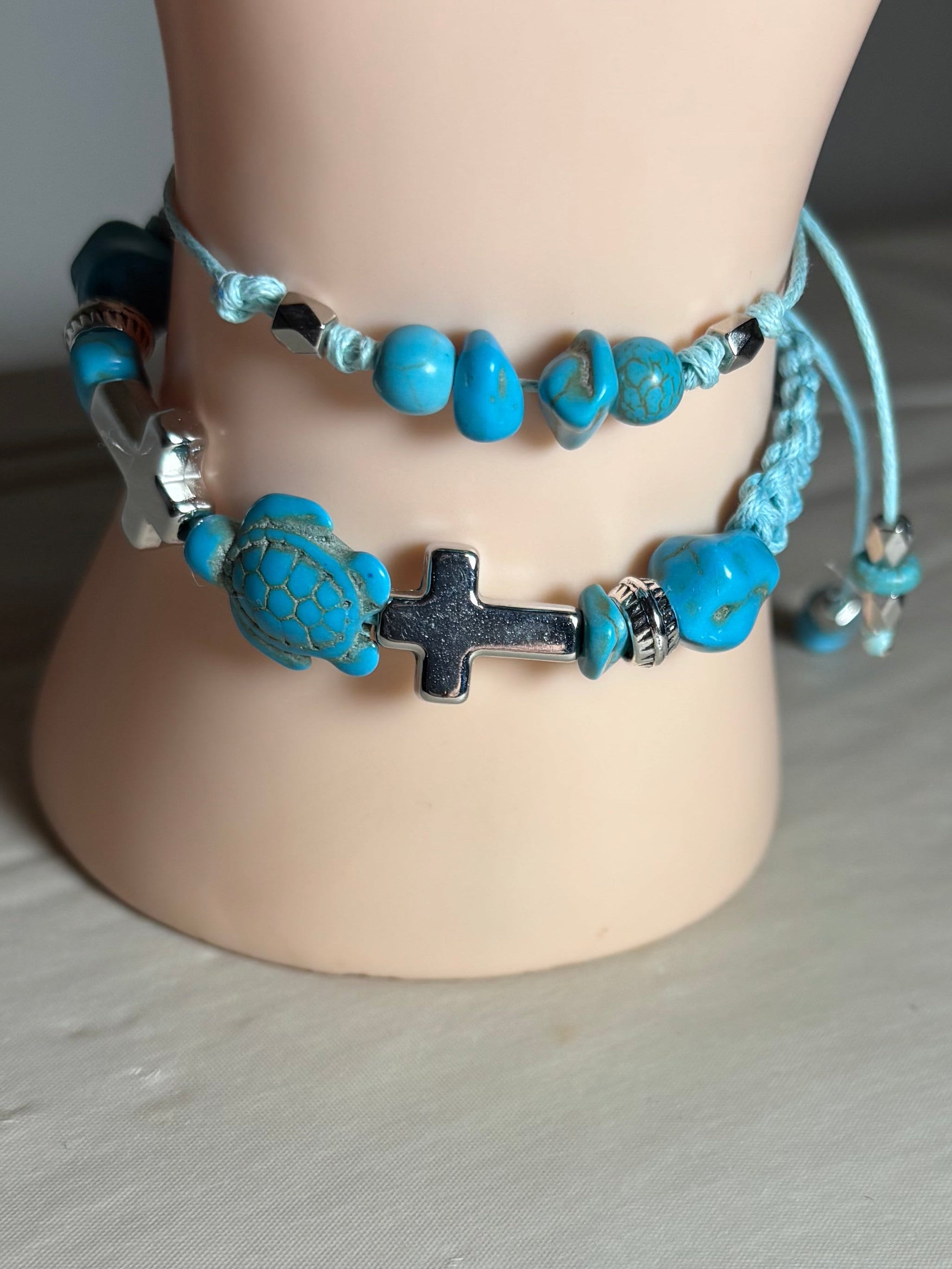 Turquoise beaded bracelet with a cross charm on a mannequin wrist.