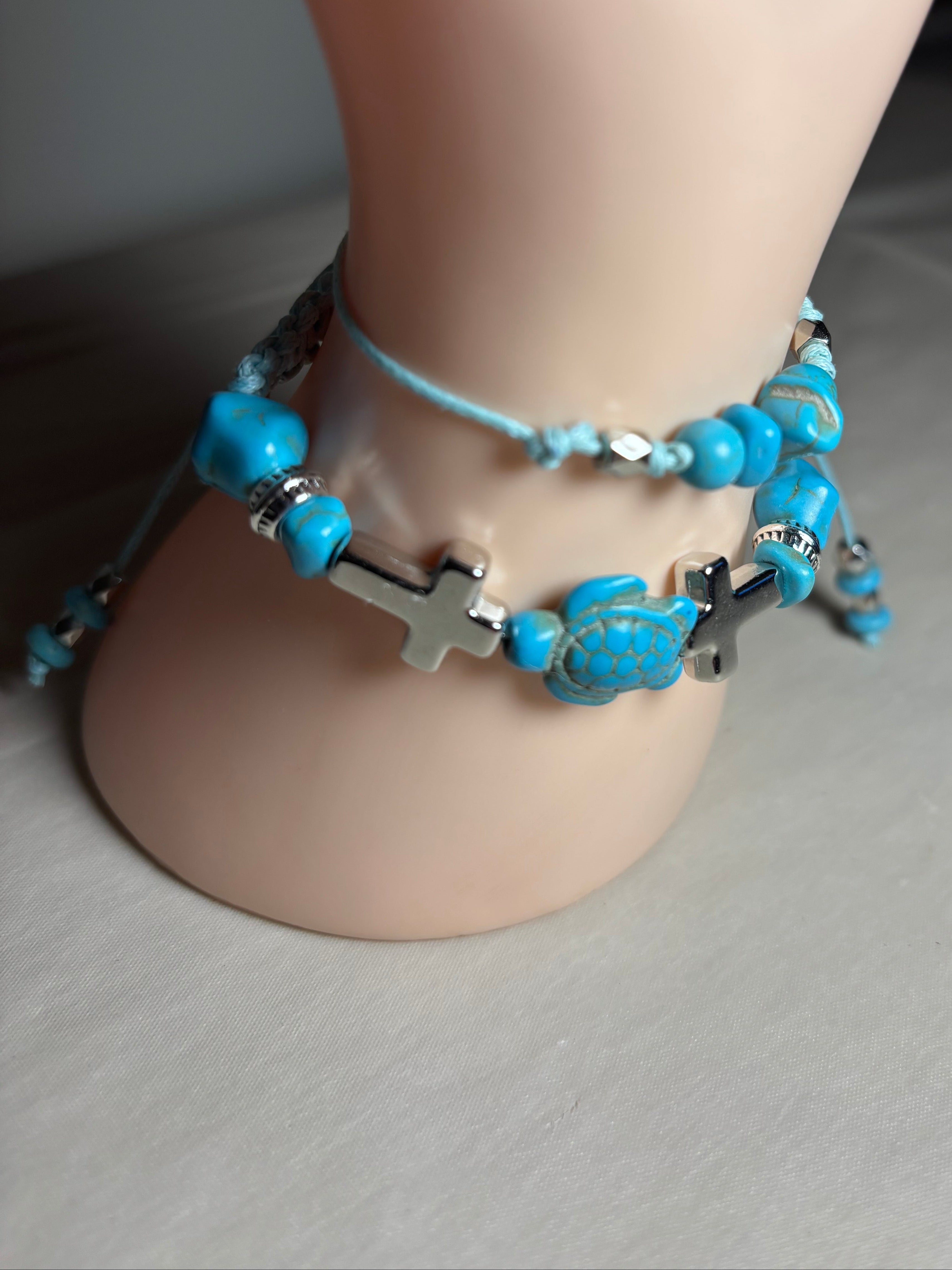 Turquoise beaded anklets with silver cross charms on a mannequin leg.