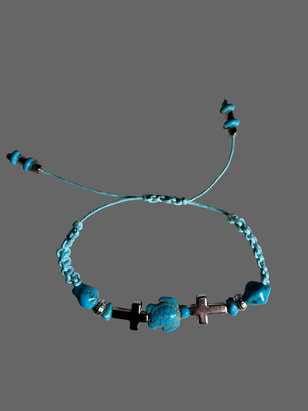 Turquoise beaded bracelet with crosses on a gray background