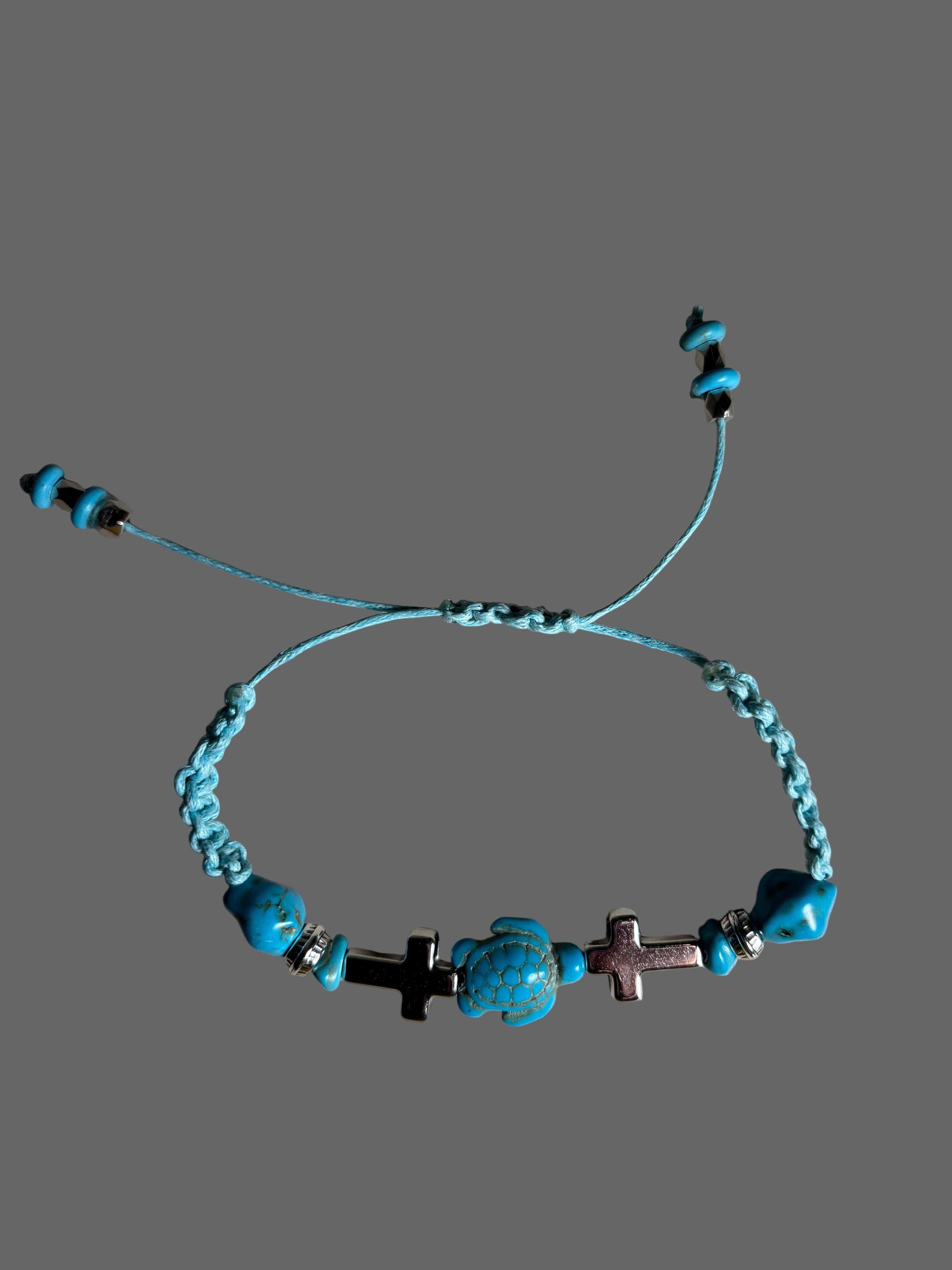 Turquoise beaded bracelet with crosses on a gray background