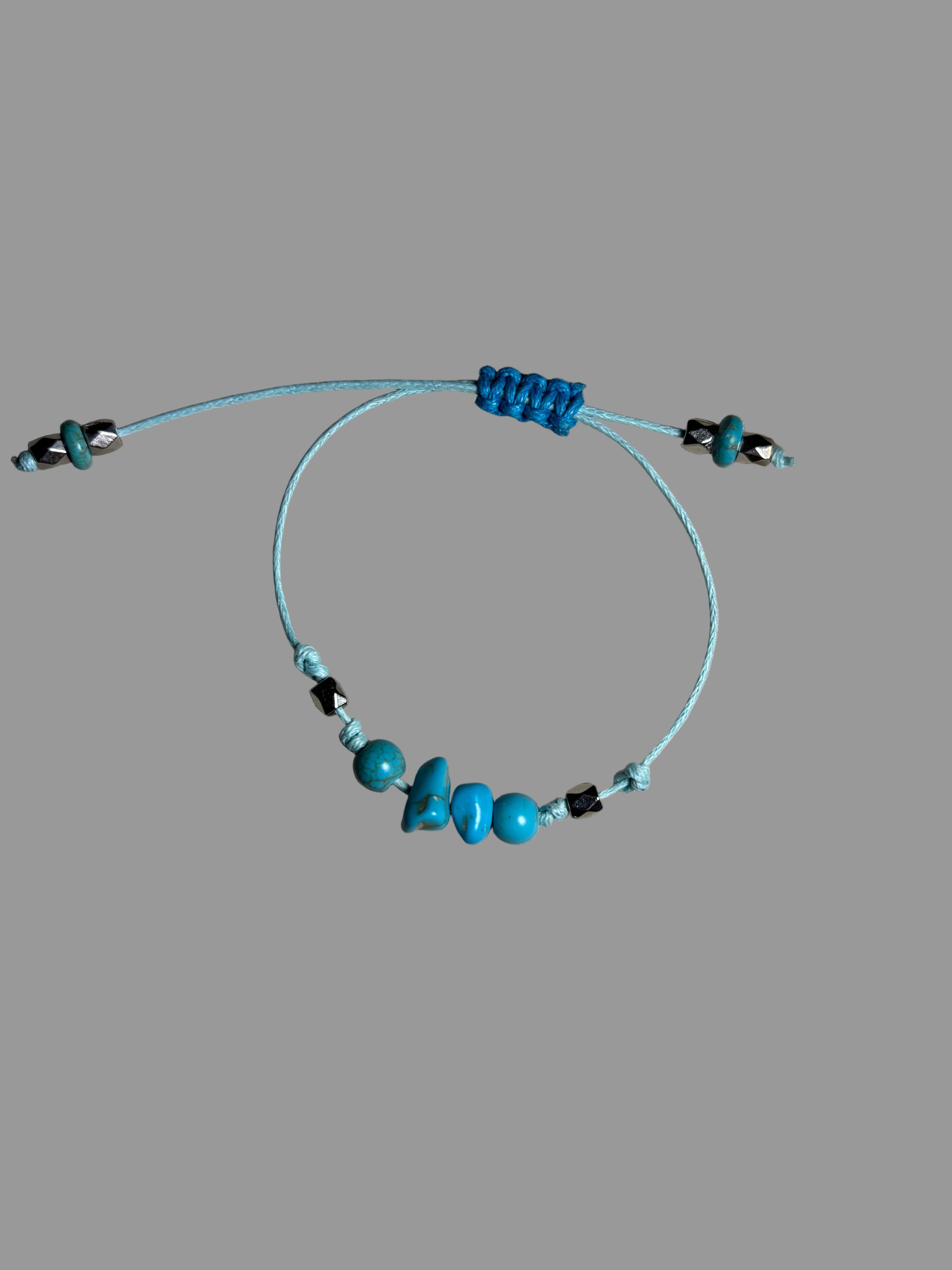 Necklace with turquoise beads and black accents on a gray surface