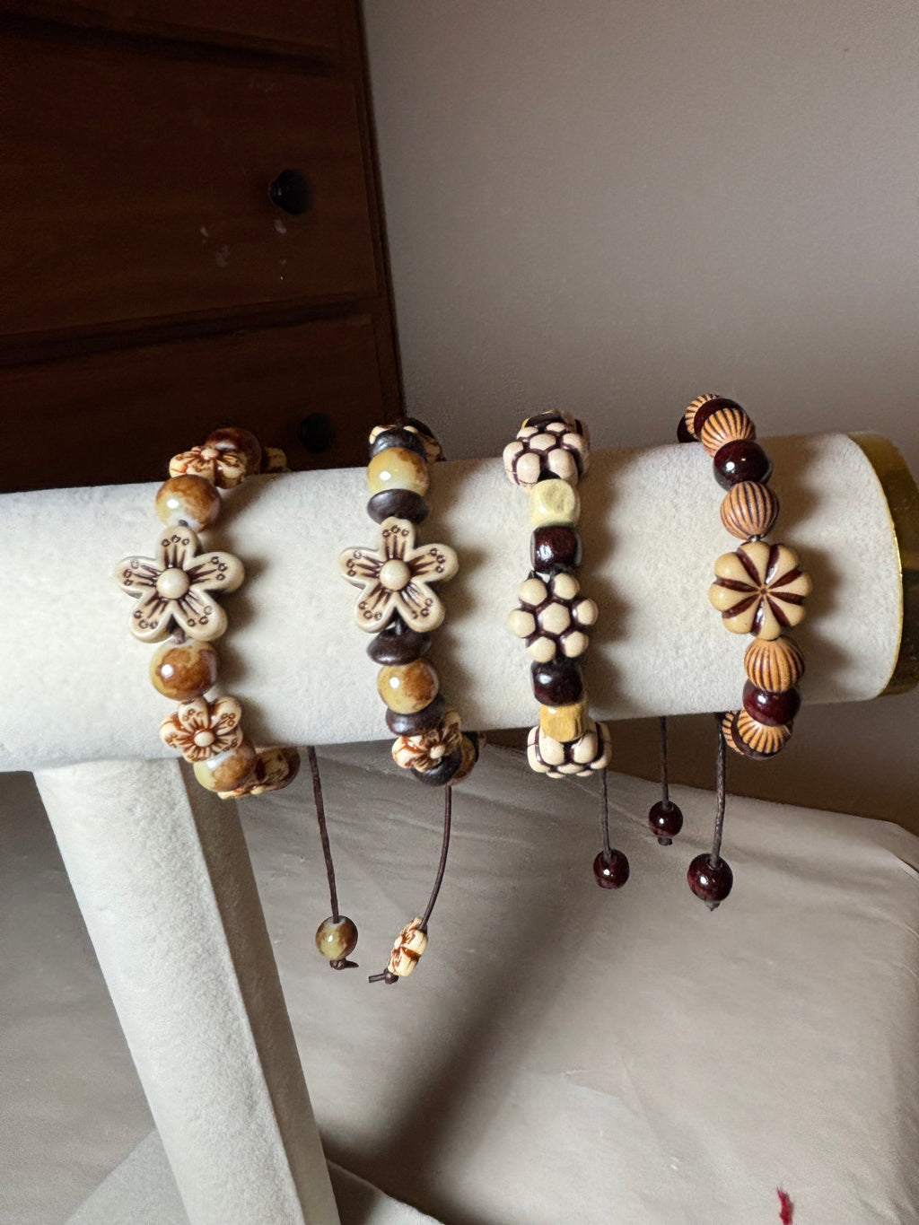 Set of beaded bracelets on a white cylindrical stand against a neutral background